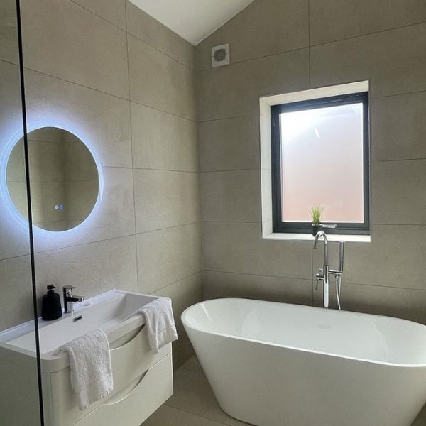 one of the bathrooms in phoenix collection pilgrim street showing image of bathtub and halo lit mirror